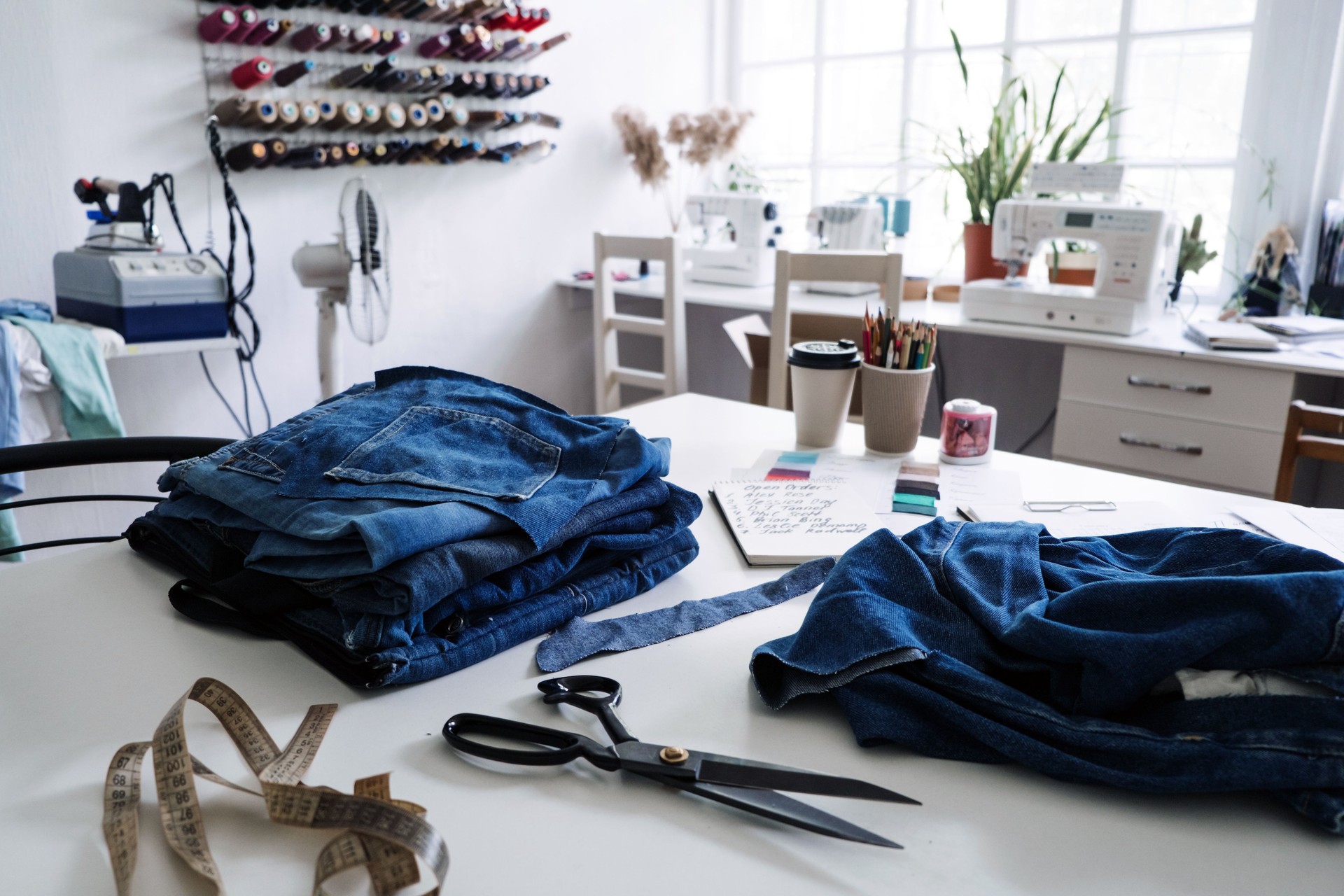 Denim Upcycling Ideas, Using Old Jeans, Repurposing Jeans, Reusing Old Jeans, Upcycle Stuff. Stack of old blue jeans, scissors, thread and sewing tools in sewing studio. Selective focus